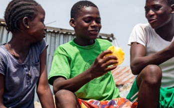 Kids eating mango and sitting down