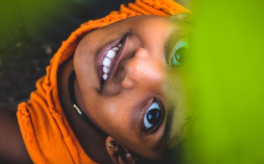 Little Indian girl smiling towards the camera in orange clothes