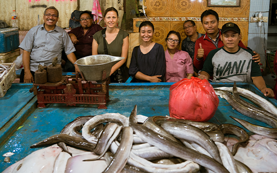 A group standing across a table with fish.
